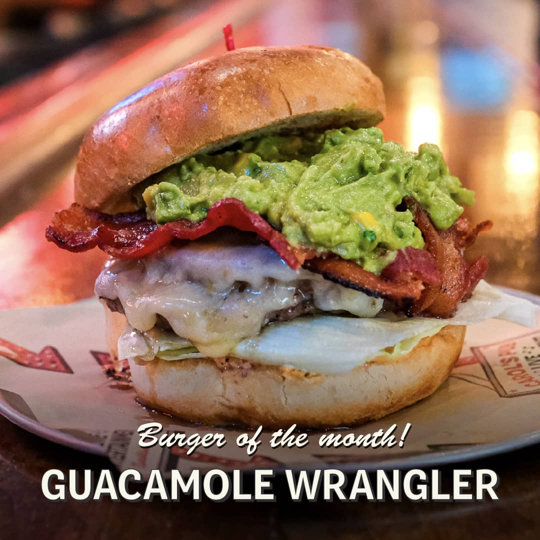 Promotional image for April's Burger of the Month at Carol's Pub: The Guacamole Wrangler Burger
